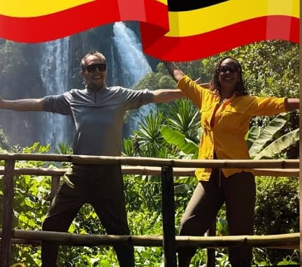 Jason and Grace, arms wide, in front of a waterfall